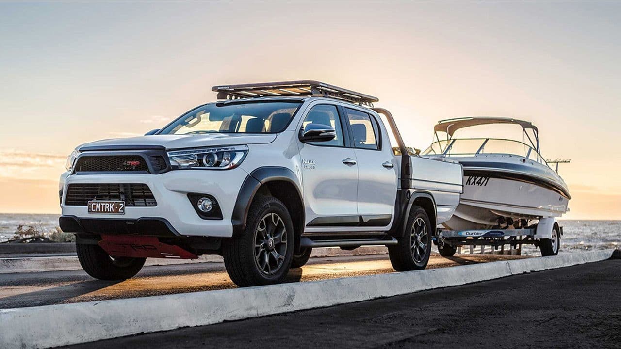 Quality photo of the truck with tray, towing a boat at sunset