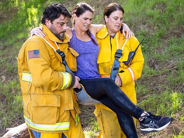 Fleetseat in use. A person being carried by two emergency personell. The support strap over their shoulders.