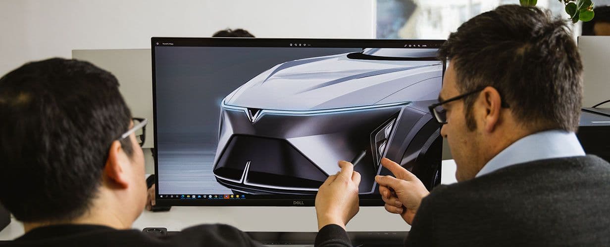 Two designers discuss a design concept on a monitor
